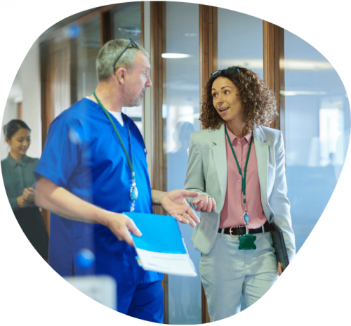 A doctor in scrubs chatting to a woman in a suit